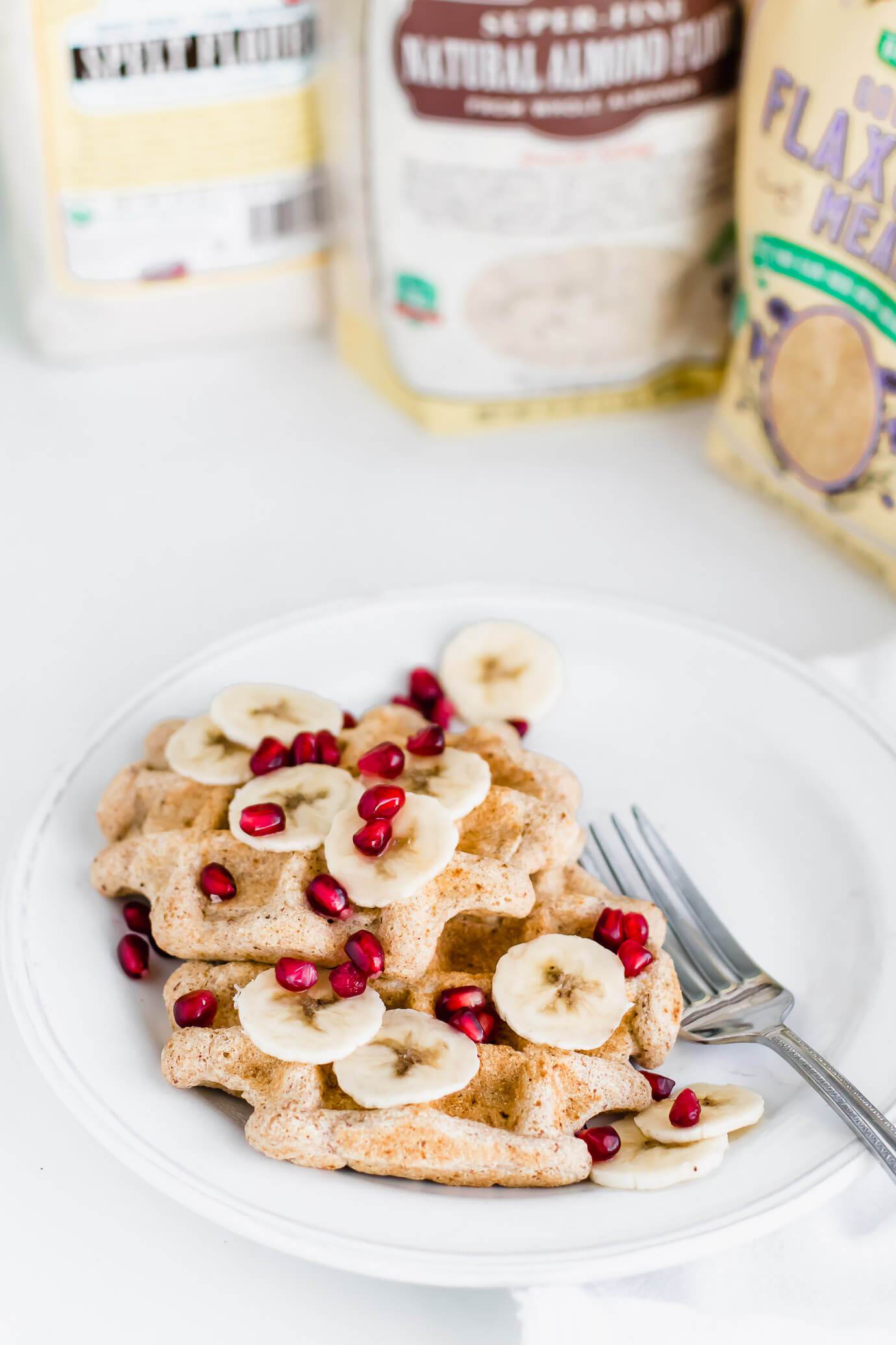 vegan spelt flour waffles topped with bananas slices and pomegranate seeds