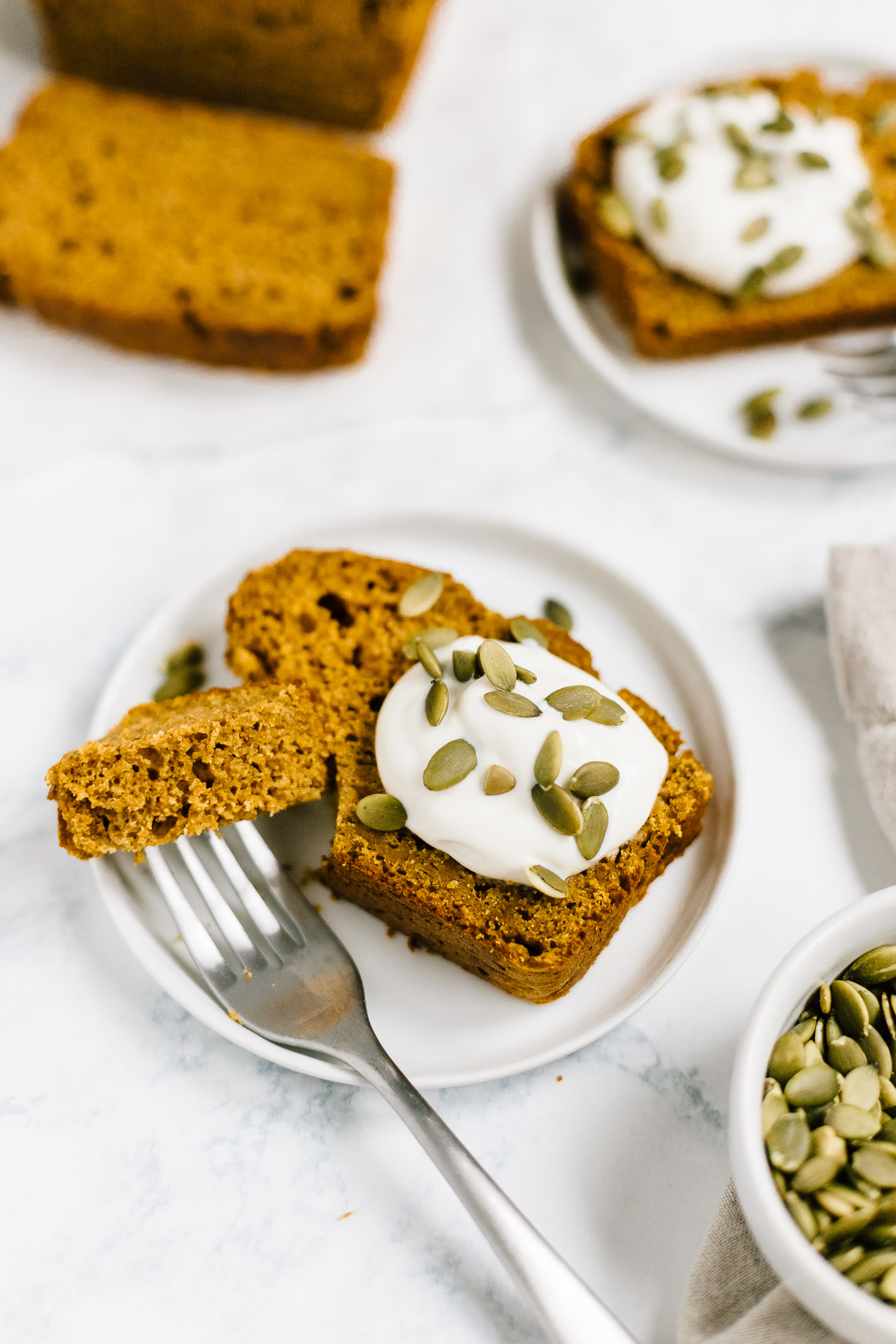 healthy pumpkin bread made with spelt flour and maple syrup on plate with dollop of yogurt