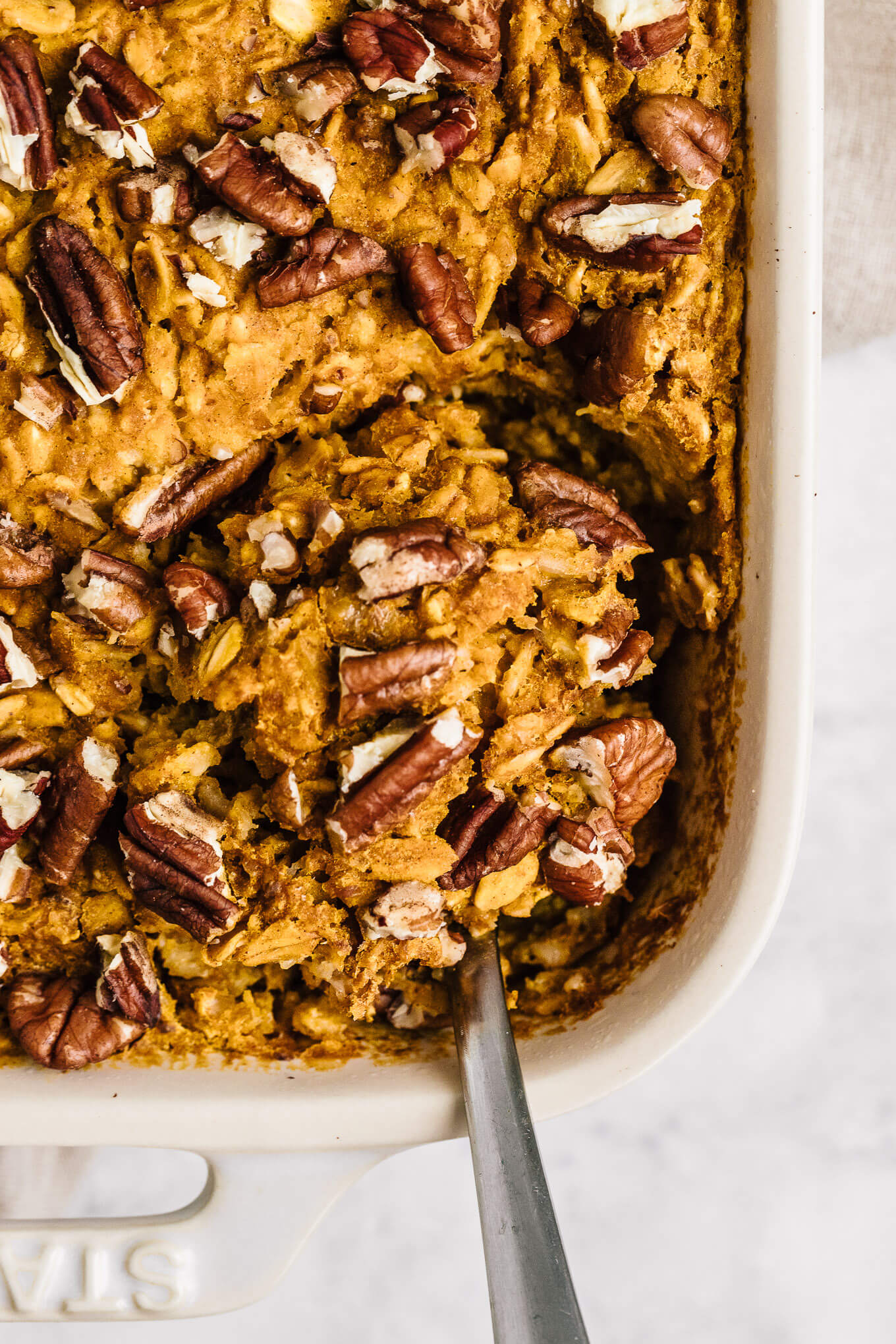 close up pumpkin baked oatmeal in Stuab pan with serving spoon