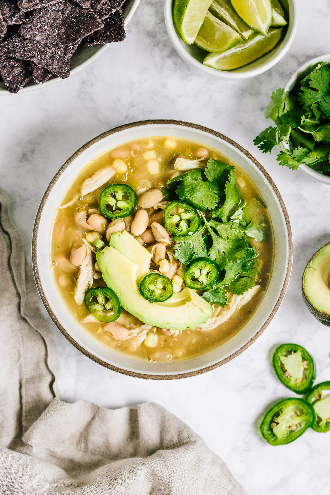 Bowl healthy white chicken chili with avocado slices, jalapenos and cilantro