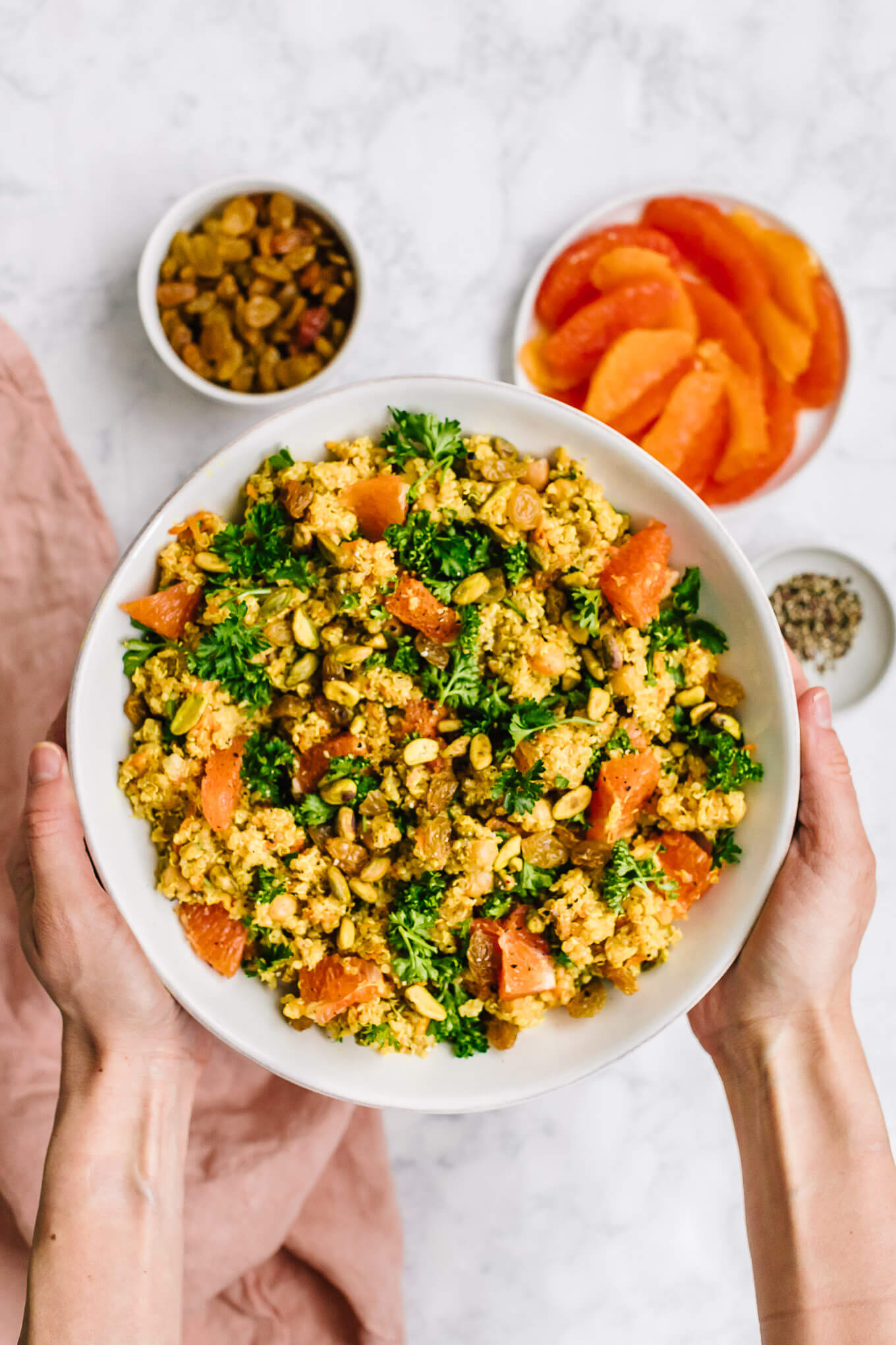 Hands holding bowl of moroccan chickpea quinoa salad