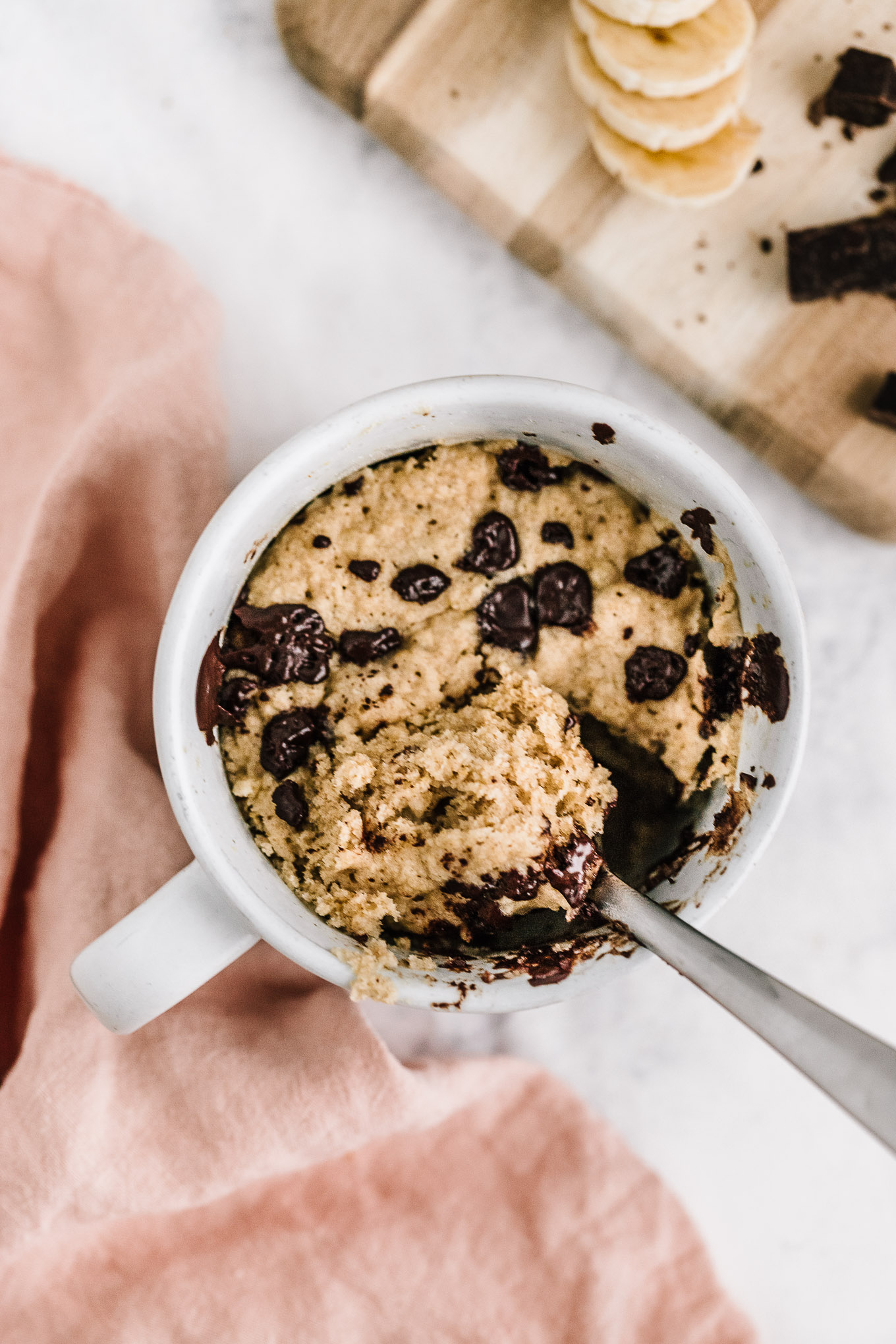 spoon scooping out vegan banana bread mug cake with chocolate chips